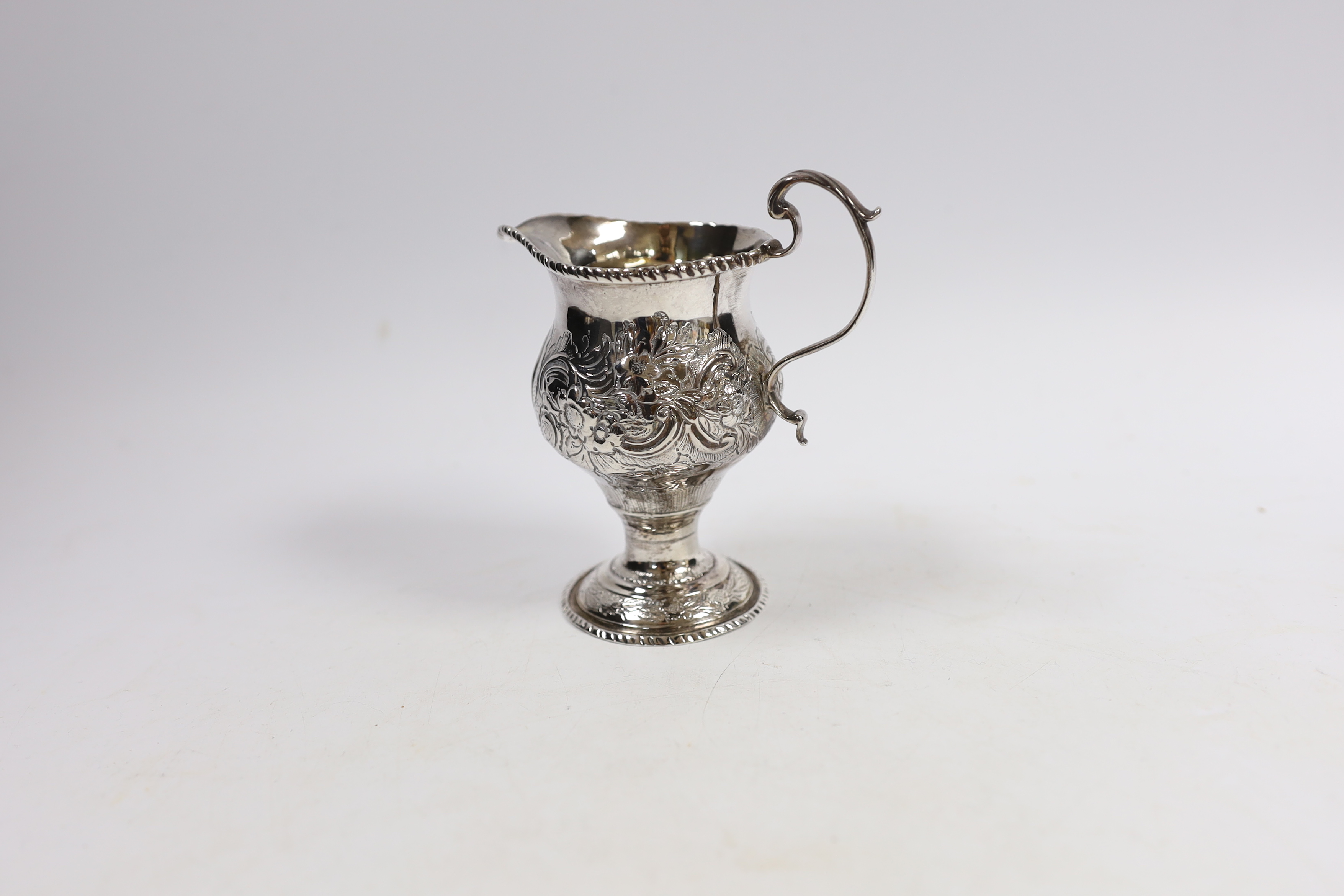 An early George III silver inverted pear shaped cream jug, with later embossed decoration, London, 1764, 11.5cm.